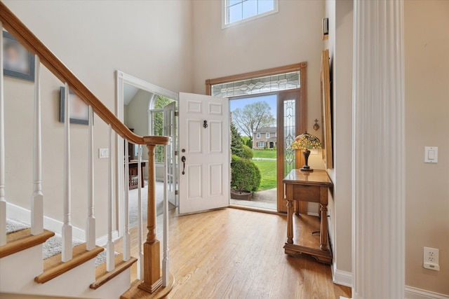 foyer with stairs, plenty of natural light, light wood finished floors, a high ceiling, and baseboards