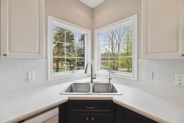 kitchen featuring a sink, light countertops, white cabinets, and decorative backsplash