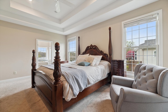 carpeted bedroom with baseboards and a raised ceiling
