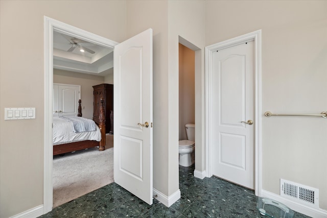 bathroom featuring toilet, baseboards, ceiling fan, connected bathroom, and a raised ceiling