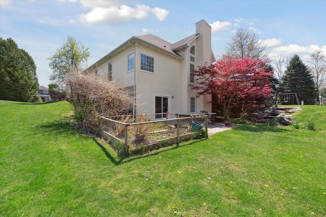 rear view of property featuring a patio, a chimney, and a lawn