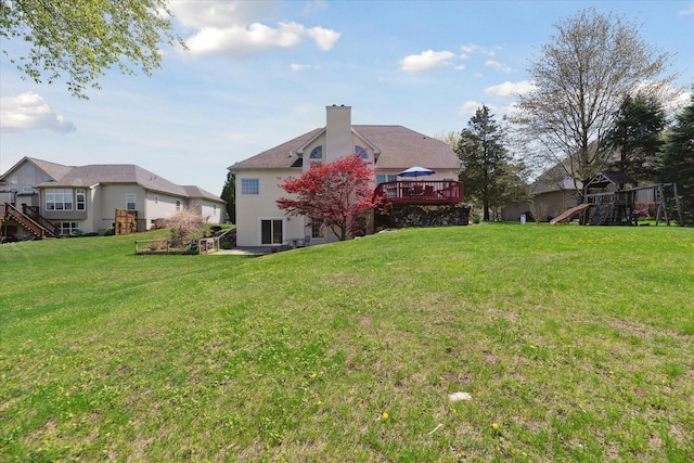 view of grassy yard featuring a playground and a deck