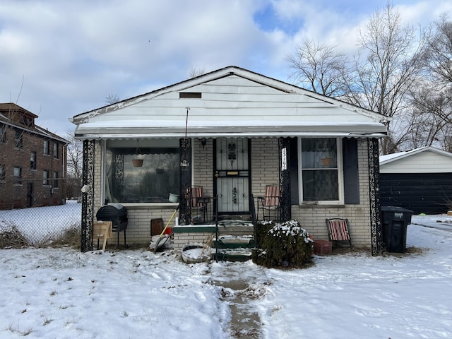 13192 Schoolcraft Rd, Detroit, MI 48227 - shotgun-style home featuring brick siding, a detached garage, covered porch, fence, and an outdoor structure