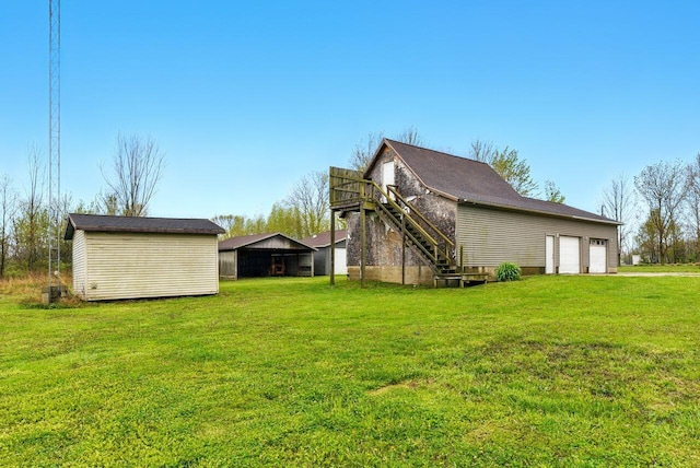 15105 Carpenter Rd, Three Oaks, MI 49128 - view of home's exterior with a lawn, stairway, a garage, and an outbuilding