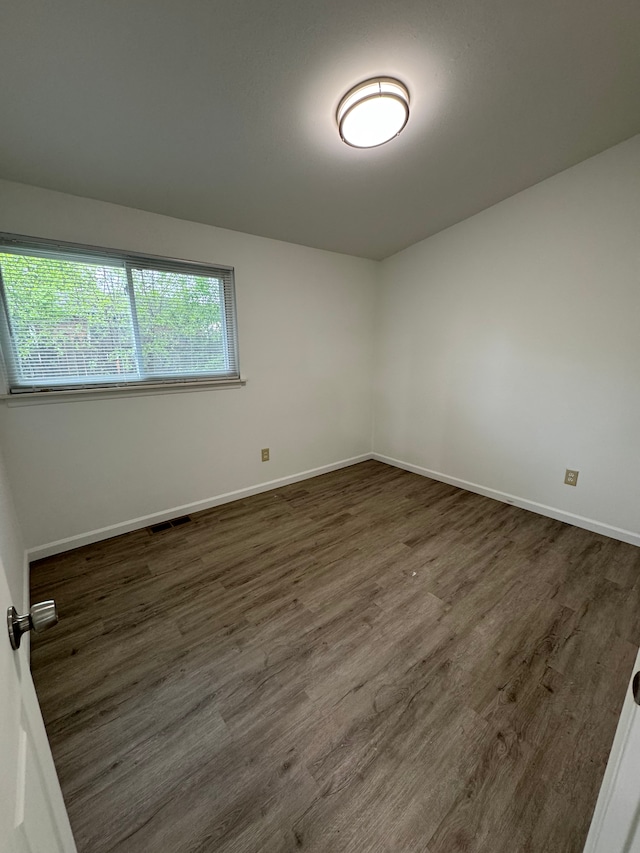 empty room featuring dark wood finished floors and baseboards