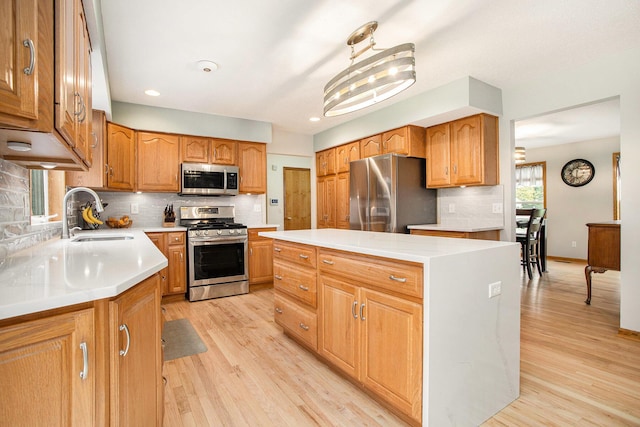 10420 Roger St, Portage, MI 49002 - kitchen featuring appliances with stainless steel finishes, a sink, a kitchen island, light wood-style floors, and decorative backsplash