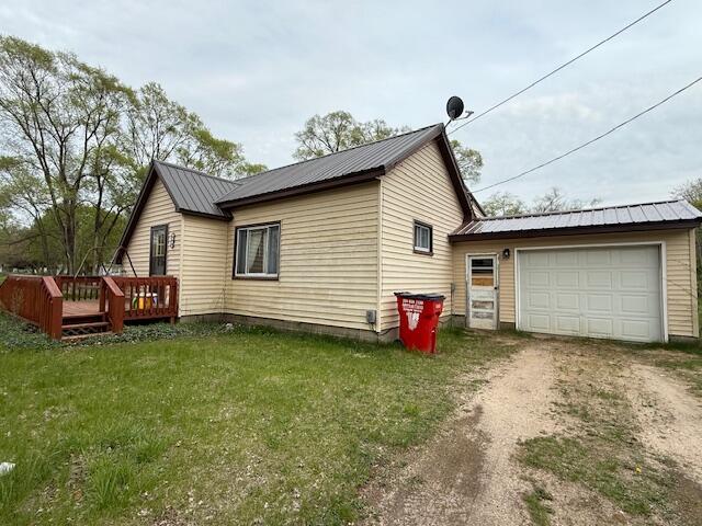 400 E Michigan Ave, Hesperia, MI 49421 - view of side of property with dirt driveway, a garage, metal roof, a yard, and a deck