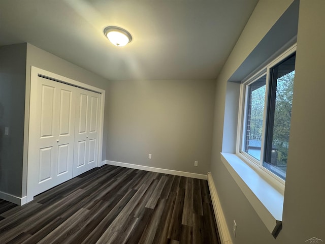 3339 S Cabaret Trl, Saginaw, MI 48603 - unfurnished bedroom with baseboards, dark wood-style flooring, a closet, and a baseboard radiator