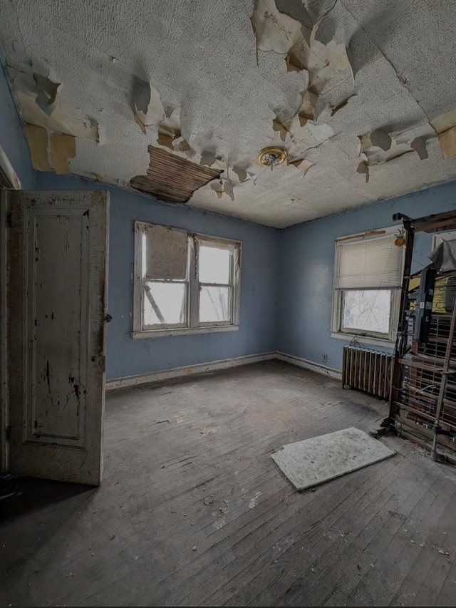 2738 Elmhurst St, Detroit, MI 48206 - unfurnished living room featuring healthy amount of natural light, radiator heating unit, a textured ceiling, and hardwood / wood-style flooring