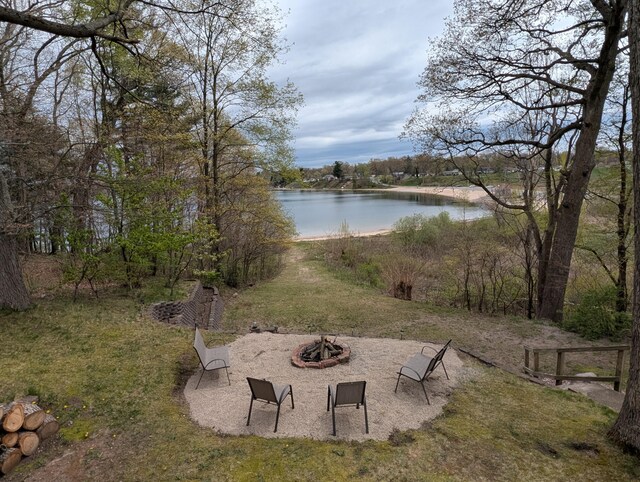 view of green lawn with a fire pit and a water view