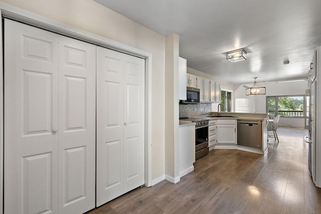 5657 Harding Ave, Muskegon, MI 49442 - kitchen featuring stainless steel appliances, a peninsula, dark wood-type flooring, a chandelier, and pendant lighting