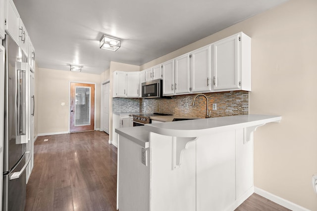 5657 Harding Ave, Muskegon, MI 49442 - kitchen featuring stainless steel appliances, wood finished floors, tasteful backsplash, a peninsula, and a breakfast bar