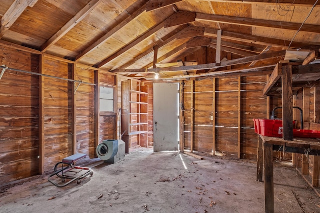 misc room featuring lofted ceiling and wood walls