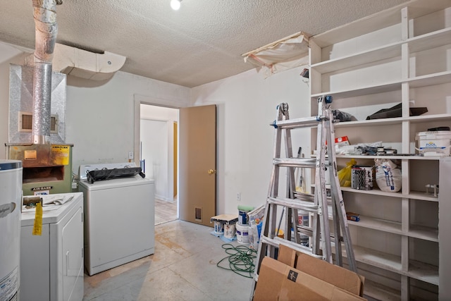 clothes washing area with washing machine and dryer, a textured ceiling, and water heater