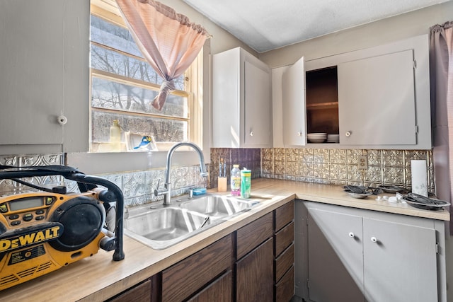 kitchen featuring a sink, light countertops, healthy amount of natural light, and decorative backsplash