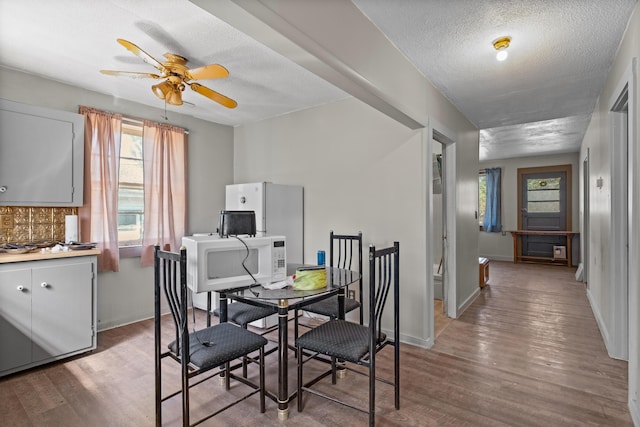 dining room with plenty of natural light, wood finished floors, a ceiling fan, and a textured ceiling