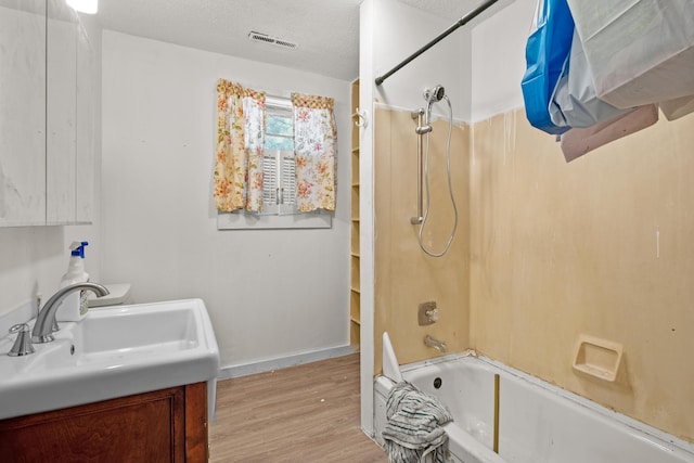 full bathroom featuring shower / bath combination, wood finished floors, vanity, a textured ceiling, and baseboards
