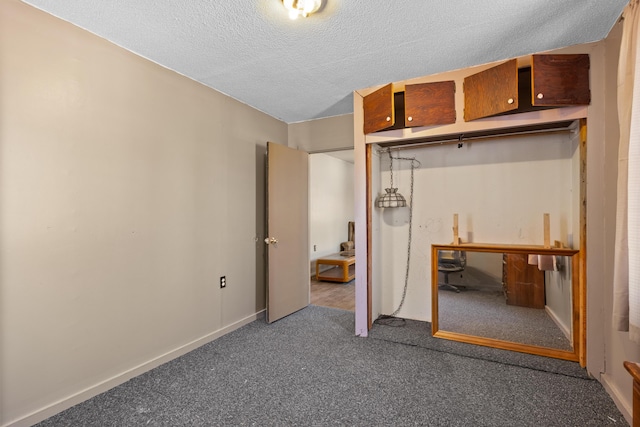 unfurnished bedroom with dark colored carpet, baseboards, and a textured ceiling