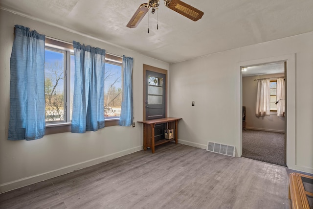 empty room featuring wood finished floors, baseboards, and ceiling fan