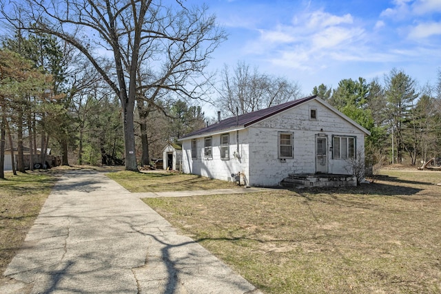 view of property exterior featuring driveway, metal roof, and a lawn