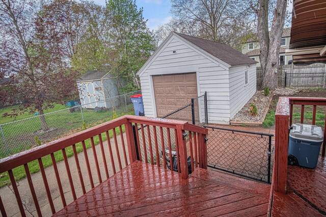 wooden deck featuring a garage, a fenced backyard, an outdoor structure, and a storage shed