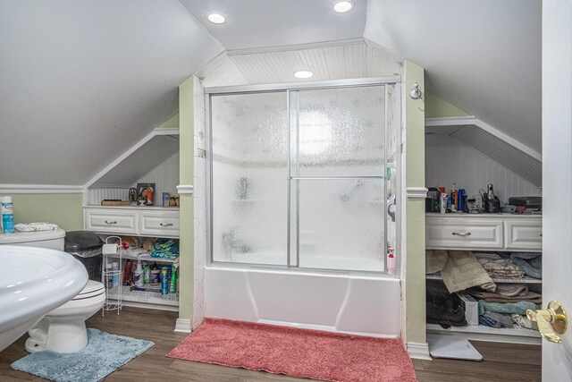bathroom with vaulted ceiling, wood finished floors, combined bath / shower with glass door, toilet, and a sink