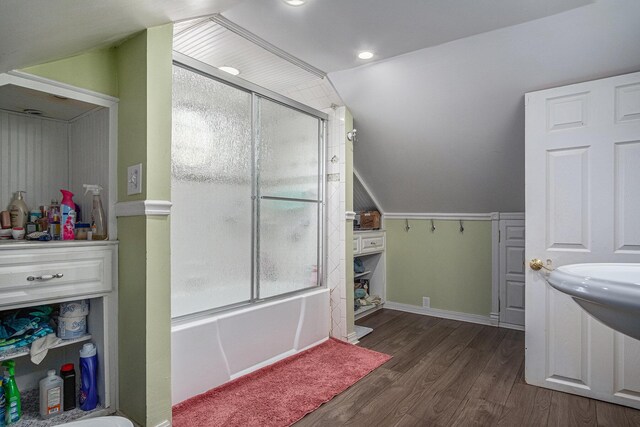 full bath featuring wood finished floors, bath / shower combo with glass door, and vaulted ceiling