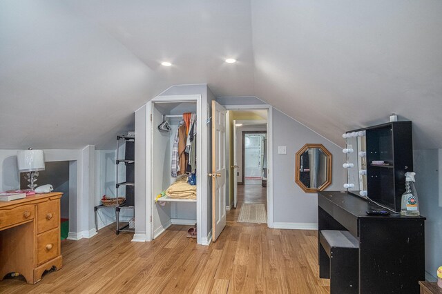 bonus room with light wood-style flooring, vaulted ceiling, and baseboards
