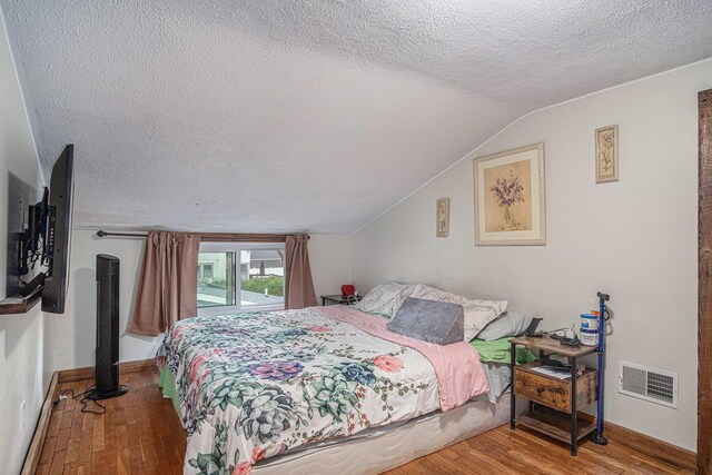 bedroom featuring a textured ceiling, wood finished floors, vaulted ceiling, and baseboards