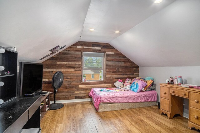 bedroom with wood finished floors, wood walls, and lofted ceiling