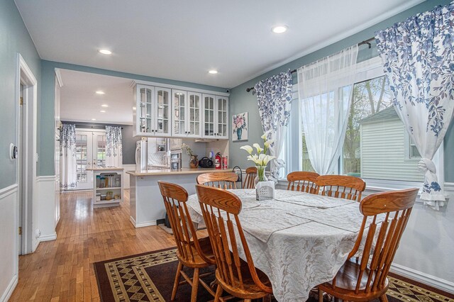 dining space with recessed lighting, light wood-style floors, and a wainscoted wall