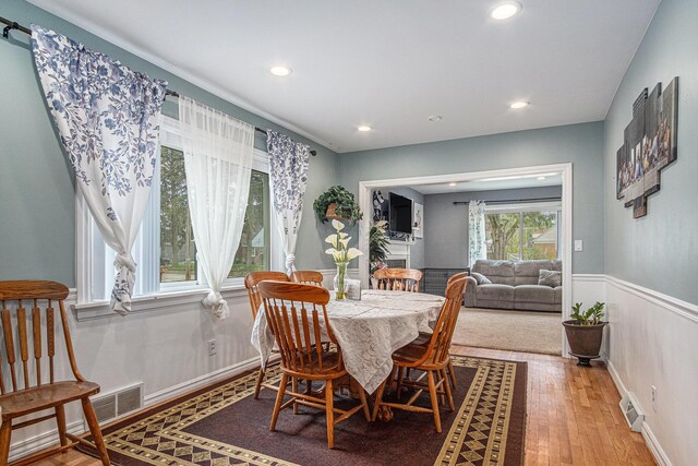 dining space featuring light wood finished floors, recessed lighting, and wainscoting