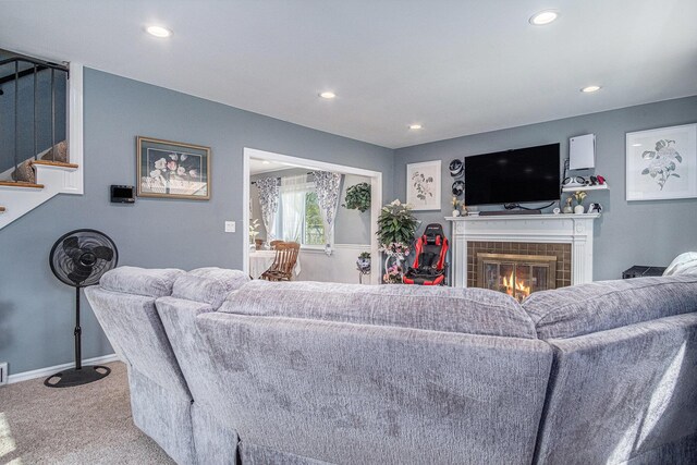 carpeted living room with stairs, a tiled fireplace, recessed lighting, and baseboards