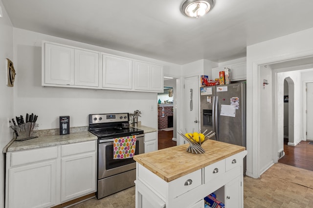 kitchen featuring stainless steel appliances, white cabinetry, arched walkways, and wood counters