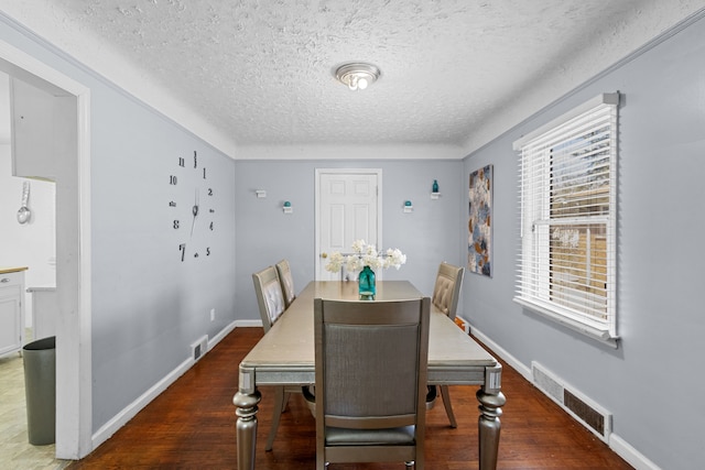 dining room with a textured ceiling, wood finished floors, and baseboards