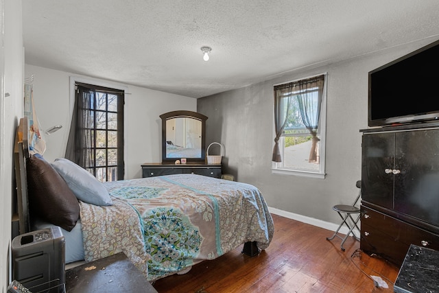 bedroom featuring wood finished floors, a textured ceiling, and baseboards