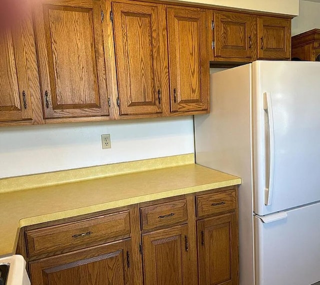 31915 M 60, Leonidas, MI 49066 - kitchen featuring freestanding refrigerator, brown cabinets, light countertops, and range