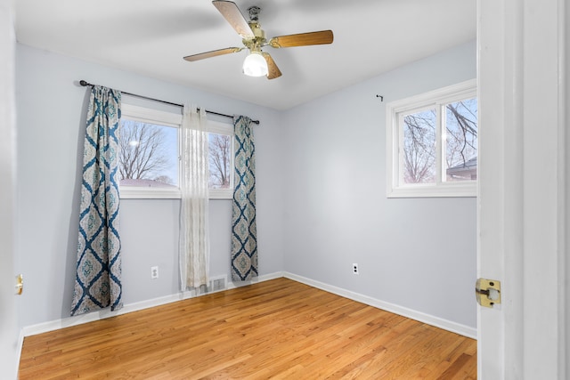 unfurnished room with wood finished floors, plenty of natural light, baseboards, and ceiling fan