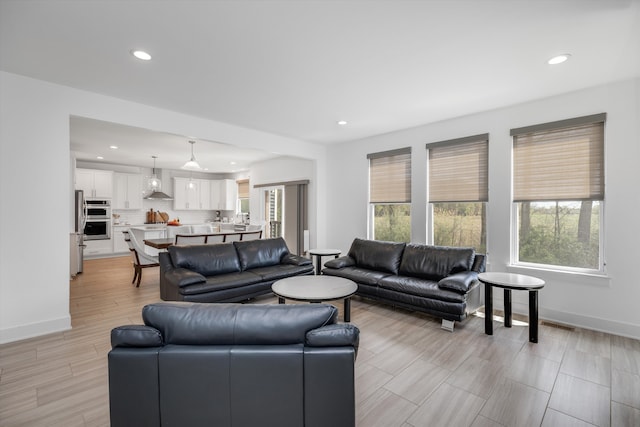 living area featuring recessed lighting, baseboards, and light wood finished floors