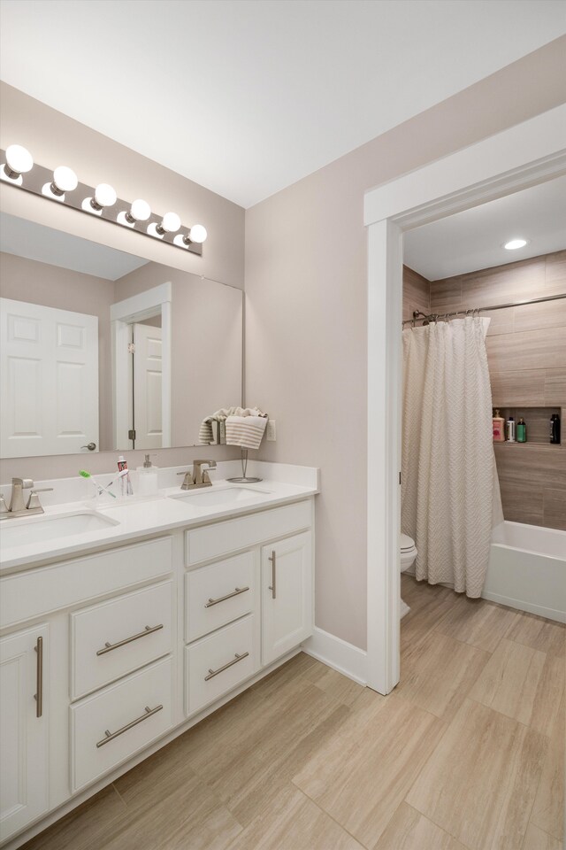 bathroom with toilet, double vanity, shower / bath combo, wood finished floors, and baseboards
