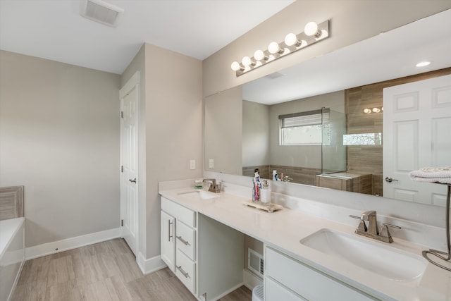 bathroom with a walk in shower, double vanity, a tub, and baseboards