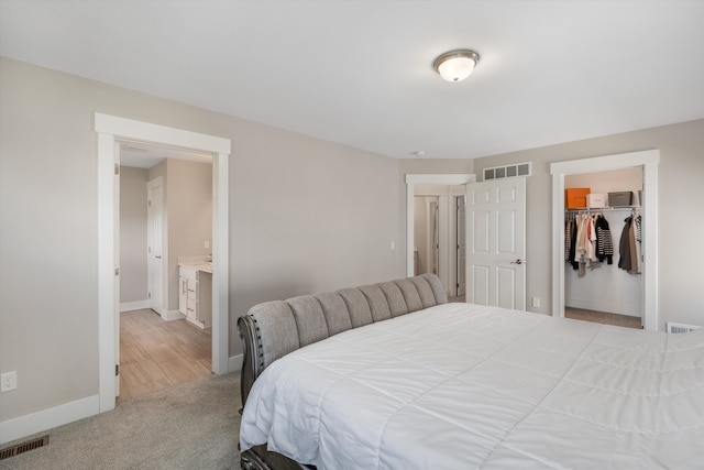 bedroom featuring baseboards, light colored carpet, a closet, and a spacious closet