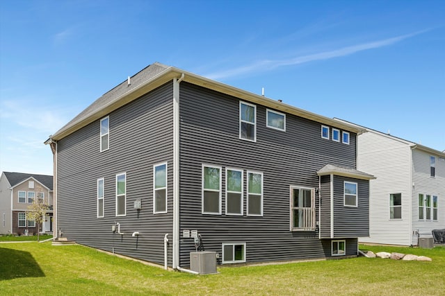 back of property with a yard and central AC unit