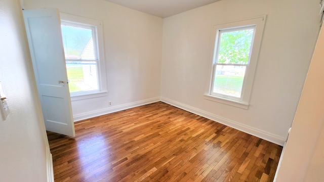 empty room featuring plenty of natural light, wood finished floors, and baseboards