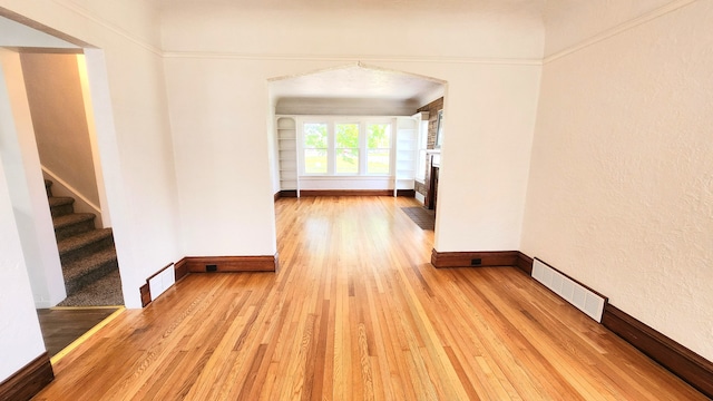 hall featuring light wood finished floors, baseboards, and stairway