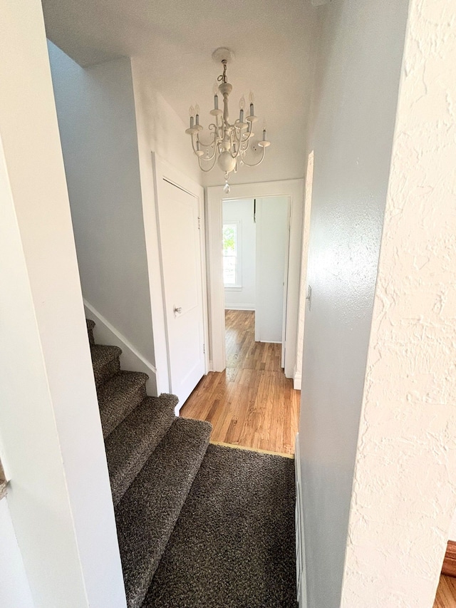 stairway featuring a chandelier, wood finished floors, and baseboards