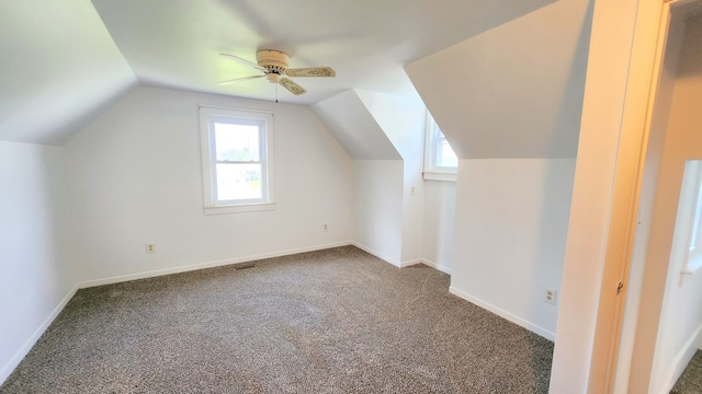 bonus room with dark carpet, vaulted ceiling, healthy amount of natural light, ceiling fan, and baseboards