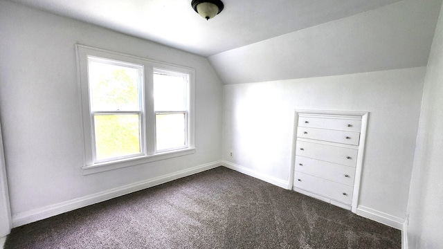 bonus room featuring dark colored carpet, lofted ceiling, and baseboards
