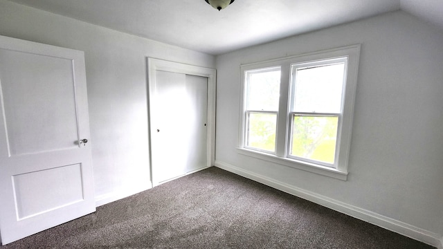 unfurnished bedroom featuring dark carpet, multiple windows, a closet, and baseboards