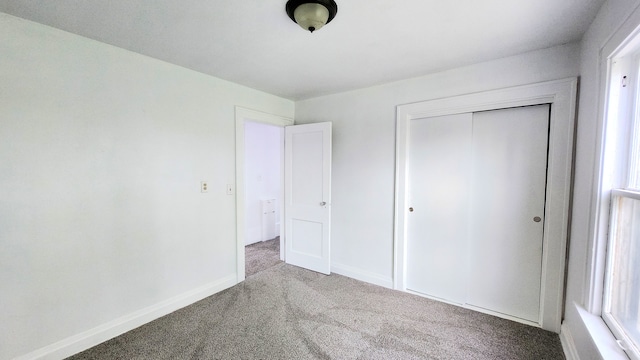 unfurnished bedroom featuring carpet flooring, a closet, and baseboards